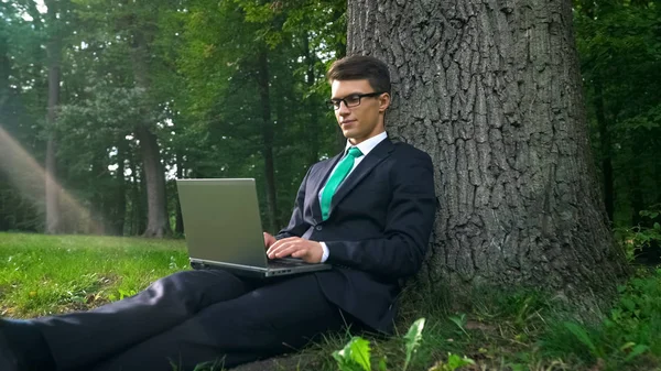 Jovem Empresário Com Laptop Sentado Debaixo Árvore Trabalhando Remotamente Parque — Fotografia de Stock