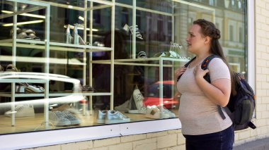 Şık butik, güvensizliği yerinde bakarak üzgün obez kız öğrenci