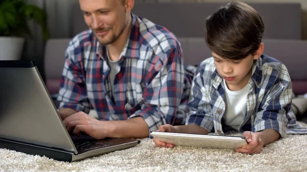Küçük Oğlu Tablet Dizüstü Bilgisayarda Çalışan Baba Süre Yerde Evde — Stok fotoğraf