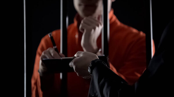 Арестованный за решеткой подписывает документы, сотрудничает с полицией
