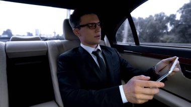 Düşünceli Yöneticisi tablet üzerinde çalışan saat trafikte kullanarak lüks araba sürme