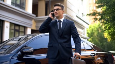 Lüks araba smartphone, haber ile mutsuz konuşurken yakın duran işadamı