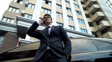 Zengin adam konuşurken telefon araba ve blok daireler, özellik karşı sigorta