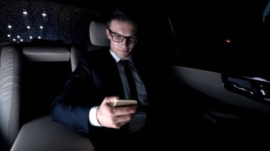 E-posta kontrol, telefon kullanarak, arabanın arka koltuğunda oturan işadamı gülümseyen
