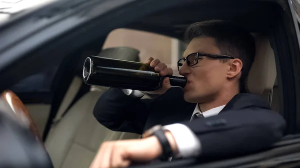 Drunk businessman drinking wine in car, accident risk, rest after stressful job