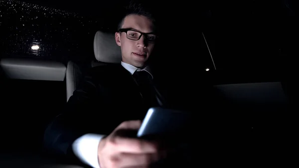 車で家に乗って 新しいビジネス アプリケーションを使用してスマート フォンで実業家のテキスト メッセージ — ストック写真