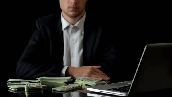 坐在笔记本电脑前的商人 桌上的钱 非法交易 — 图库照片