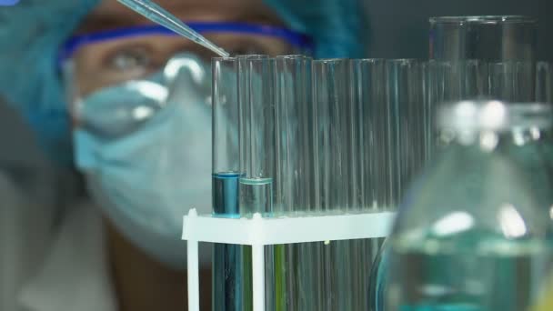 Biochemik nalewanie cieczy w probówce z niebieską substancją i sprawdzenie reakcji — Wideo stockowe