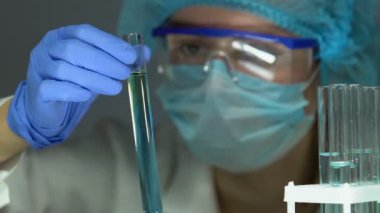 Laboratuar asistanı test tüpünde mavi sıvıyı kontrol ederek, tablette test sonucu ekleme