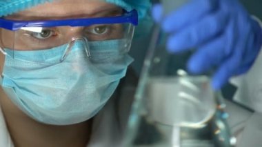 Tıbbi Laboratuar işçisi şeffaf sıvı ile Flask tutarak, su kalitesini kontrol