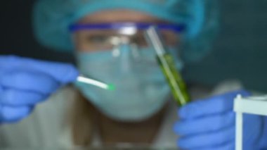 Laboratuar biyolog bitki ile test tüpü içine yeşil reaktif koyarak, deney