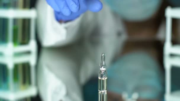 Ο φαρμακοποιός ελέγχει το φιαλίδιο του φαρμάκου στο εργαστήριο, αντιιικό εμβόλιο, αντιβιοτικό — Αρχείο Βίντεο