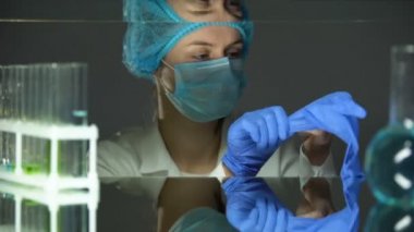 Laboratuar asistanı eldiven koyarak, kimyasallar ile çalışma sırasında kaza önleme