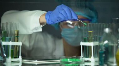 Laboratuar asistanı tüp yeşil toz ekleme ve sekme üzerine sonuç yazarak, teknoloji