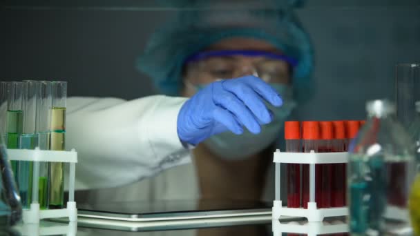 Лабораторний технік, що аналізує трубку з сироваткою крові та набирає результати на планшеті — стокове відео