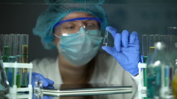 Investigador médico analizando ampollas con vacunas y escribiendo notas sobre pestañas, ciencia — Vídeo de stock