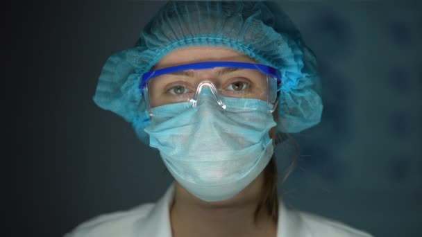 Wetenschapper in beschermende uniform op zoek naar camera, moe Doctor na de operatie — Stockvideo