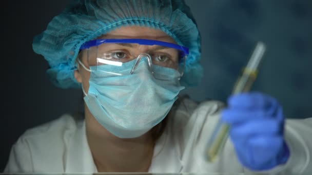 Lab assistant looking at tube with transparent yellow liquid, biofuel testing — Stock Video