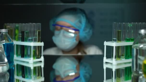 Asistente de laboratorio mirando a la cámara, científico llevando a cabo la investigación experimental — Vídeo de stock