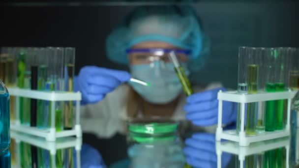 Asistente de laboratorio agregando polvo verde al tubo con planta verde, influencia del fertilizante — Vídeos de Stock