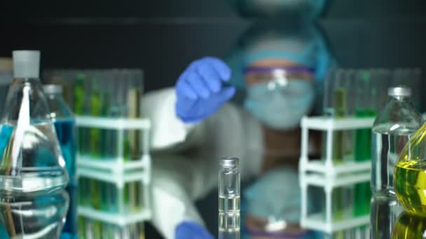 Ученый держит бутылку с прозрачной жидкостью для инъекций, исследования антибиотиков — стоковое видео