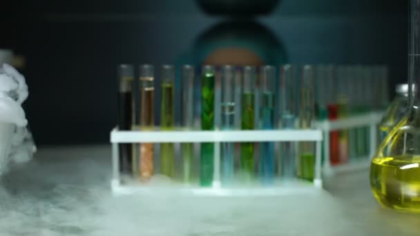 Біолог відкриває холодильник і приймає трубку з зеленою рослиною в консерванті — стокове відео