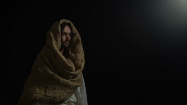 Jesus im Gewand kommt aus der Dunkelheit und hebt die Hände, appelliert an Gott, an den Glauben — Stockvideo