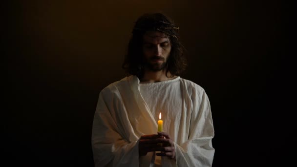 Бог сын в терновом венце держа свечу, святой мученик молится за людей, доброта — стоковое видео