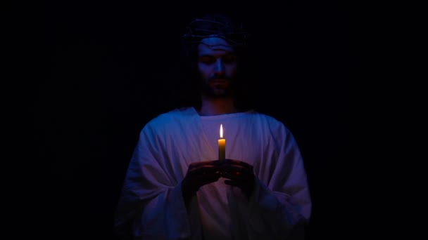 Christian saint in crown of thorns holding candle in darkness praying for people — Stock Video