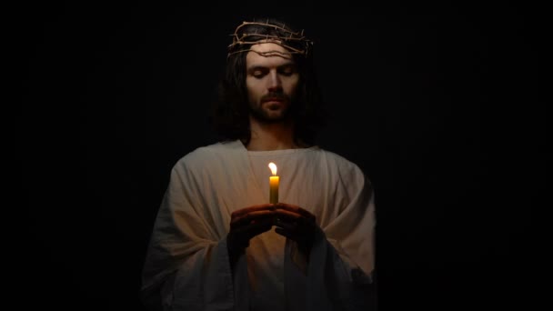 Jesus Christ in crown of thorns holding candle and praying for god blessing hope — Stock Video