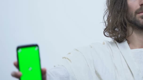 Иисус Христос показывает смартфон с зеленым экраном, онлайн приложение Библии — стоковое видео