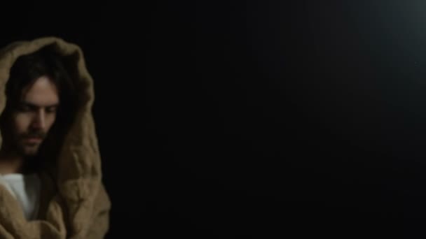 Jesus Christus zeigt Wasserbecher vor dunklem Hintergrund, leidende Menschen helfen — Stockvideo