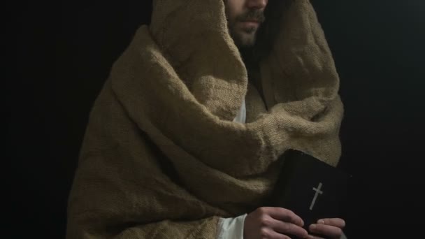Иисус Христос показывает святую Библию на камеру, каноны Бога, символ религиозной жизни — стоковое видео