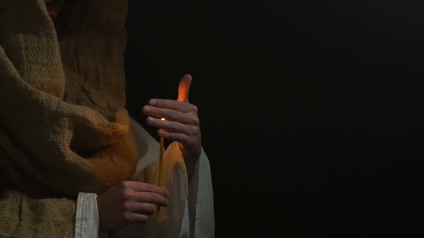 Прихожанин в халате держит горящую свечу, молится Богу, просит о помощи — стоковое видео