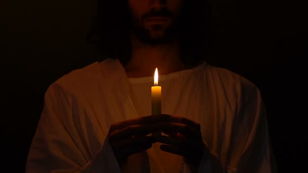 Jesus Kristus med brinnande ljus stående i mörker, föra hopp och tro — Stockvideo