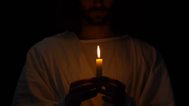 Jesus Christ in crown of thorns with burning candle against darkness, rescuing — Stock Video