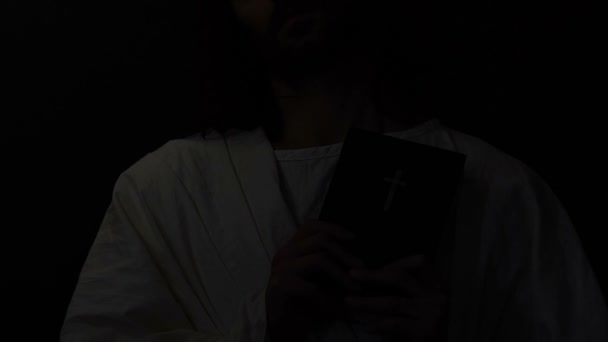 Иисус Христос с закрытыми глазами в терновом венце, держа библию, распятие — стоковое видео