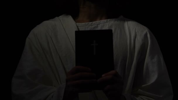 神聖な聖書を抱いているローブの宗教的人心の近くに、キリスト教会、信仰 — ストック動画