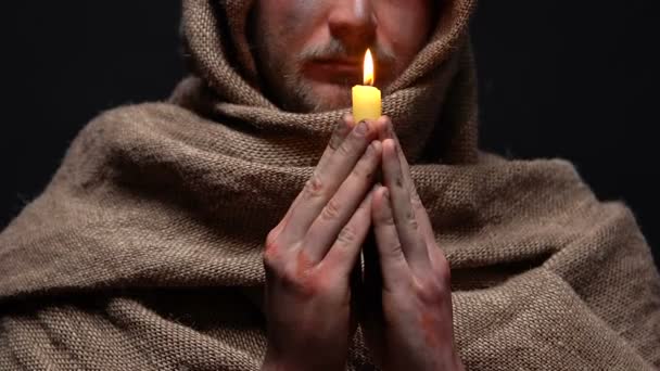 Miserable man praying with burning candle in hands, asking for forgiveness, hope — Stock Video