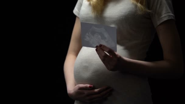 Jeune femme enceinte tenant un enfant radiographie, maternité heureuse, attente du bébé — Video