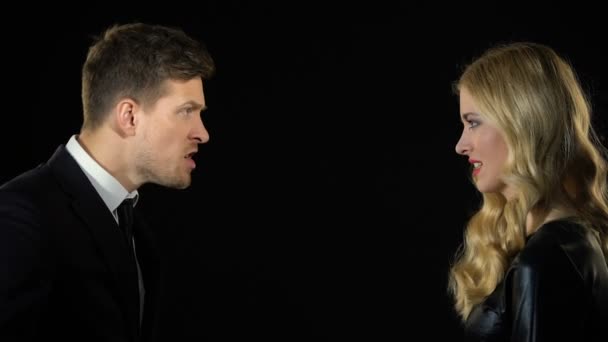 Молодая пара эмоционально спорит на черном фоне, недоразумение — стоковое видео