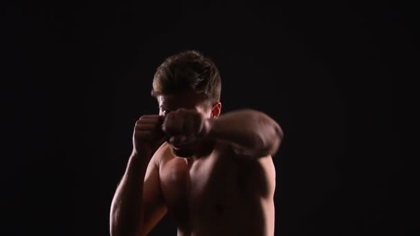 Мускулистый человек теневой бокс с интенсивным взглядом на камеру, мотивированный к успеху — стоковое видео