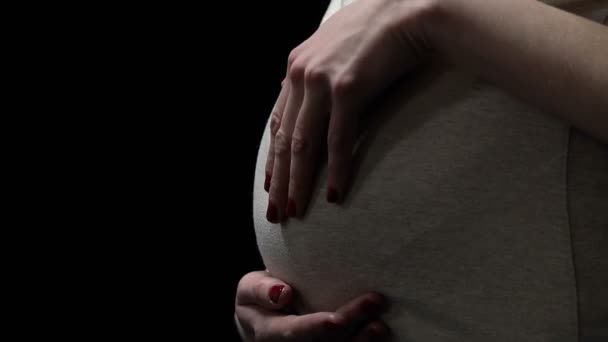 Вагітна жінка погладжує живіт ізольовано на чорному, ризики для здоров'я під час вагітності — стокове відео