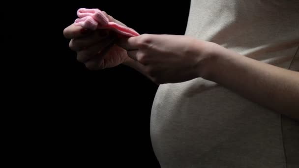 Mujer embarazada sosteniendo calcetines rosados aislados en negro, ansiosos por la salud del bebé — Vídeo de stock