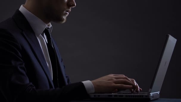 Elegante hombre de negocios escribiendo en el ordenador portátil aislado en negro, trabajando duro en el proyecto — Vídeo de stock