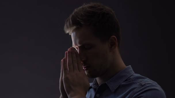 Молодий чоловік щиро молиться, шукаючи вирішення складних життєвих проблем — стокове відео