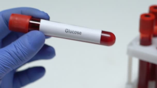 Глюкоза, лаборант, держащий образец крови в трубке крупным планом, медицинский осмотр — стоковое видео