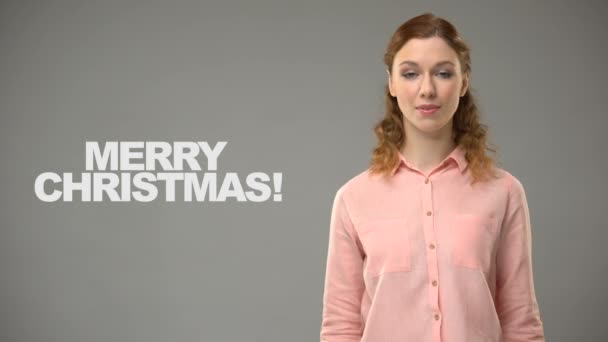 Surda senhora dizendo Feliz Natal em língua de sinais, texto no fundo, surdez — Vídeo de Stock