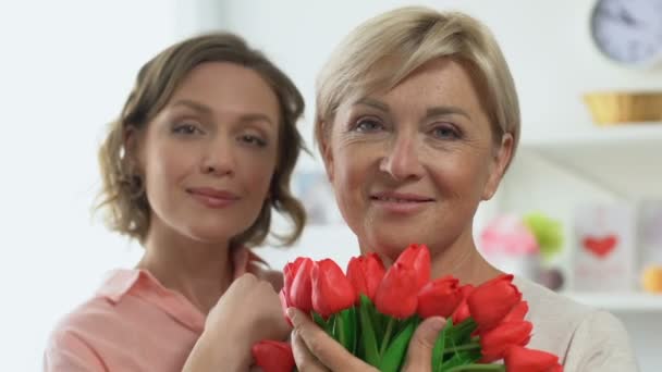 Retrato de hija adulta y madre sosteniendo tulipanes, celebrando el Día de la Mujer — Vídeo de stock