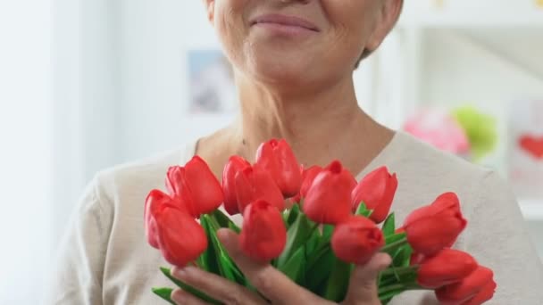 Мать средних лет, пахнущая тюльпанами, счастливо улыбающаяся, морщины на лице крупным планом — стоковое видео
